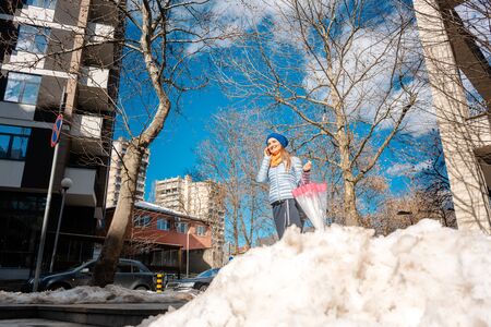 Woman walking through melting snow in late winter talking on the phoneの写真素材