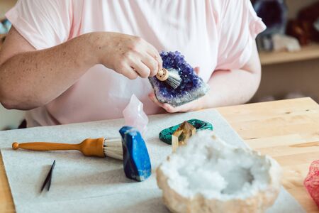 Woman brushing an amethyst in her workshopの写真素材