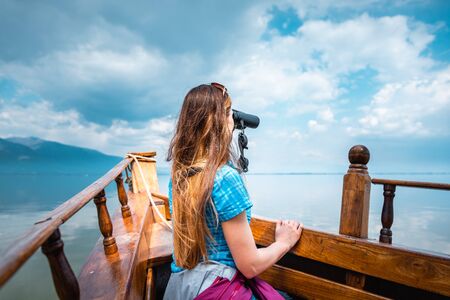 Woman on a boat with binocular watching birds in nature