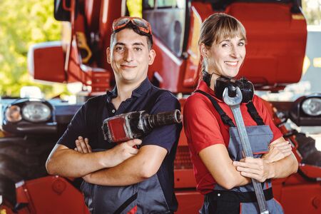 Two machinists for farm machinery in their garage standing shoulder to shoulderの写真素材