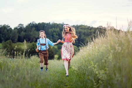 Mother and son in Bavaria running down a path beside a meadowの写真素材