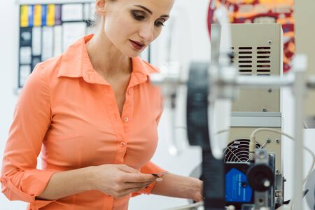 Worker woman checking textile label fresh from the printing machine