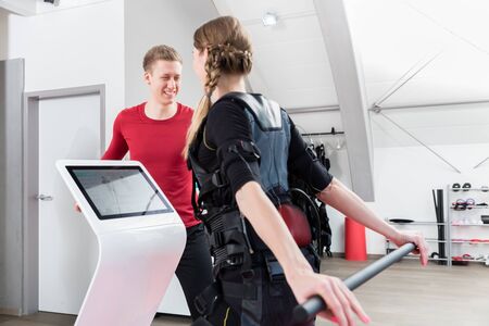 Woman stretching in the EMS gym with personal trainer watching her