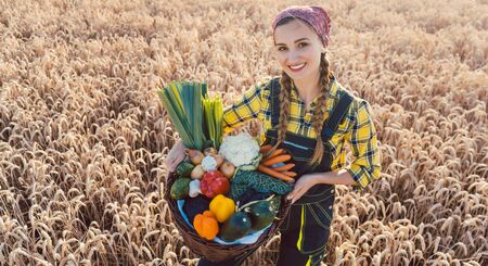 Farmer woman offering healthy vegetables in rural environmentの写真素材