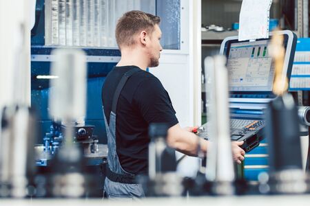 Worker in industrial workshop programming a cnc machine