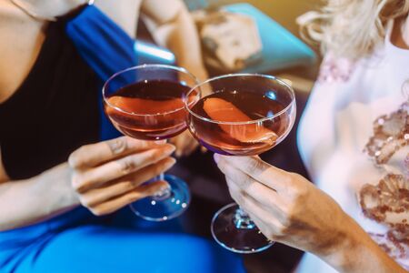 Close up on women holding cocktails in a bar toastingの写真素材