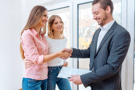 Real estate broker shaking hands with two women tenantsの写真素材
