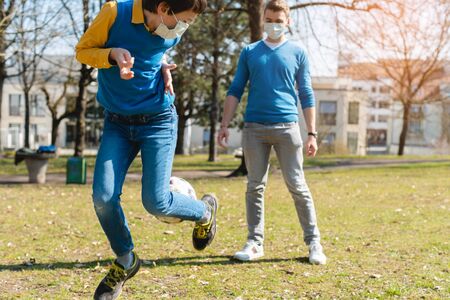 Dad and son playing soccer in park during coronavirus crisis on beautiful day