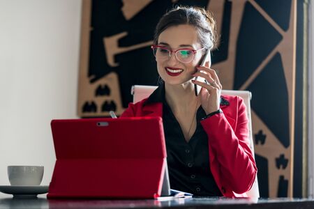 Businesswoman working with her computer while being on the phone talking to a customer