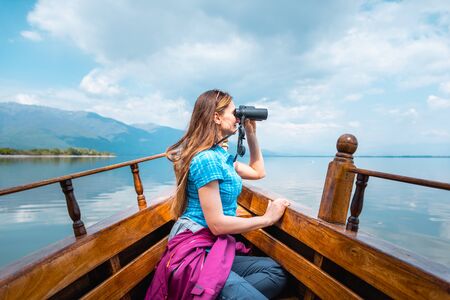Woman on a boat with binocular watching birds in nature
