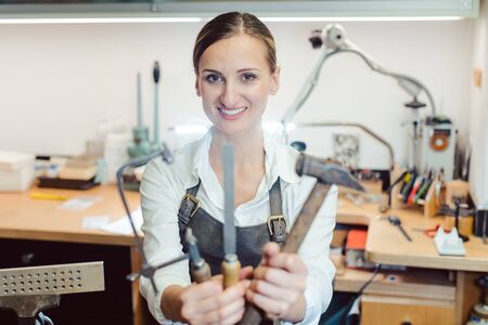 Jewelry designer in her workshop boating with her tools looking at the cameraの写真素材
