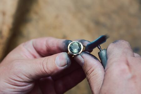 Closeup on hands of diligent goldsmith working on a ring in his workshopの写真素材