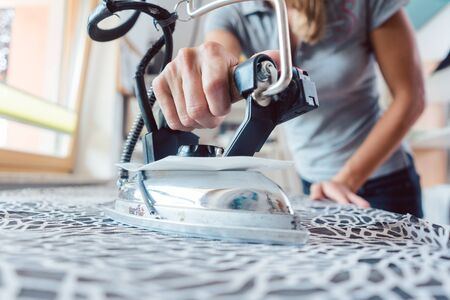 Seamstress with tailor iron ironing fabric