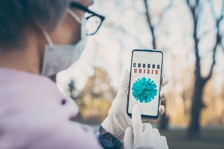 Senior woman using Coronavirus tracking app on her phone outdoorsの写真素材