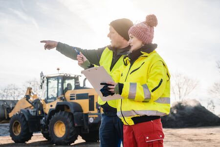 Manager and worker in biomass compost works engaged in discussion about the schedule