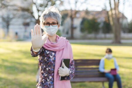 Grandmother giving stop sign to covid-19 protecting her grandson and herselfの写真素材