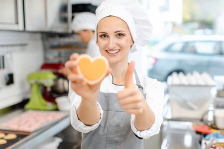 Pastry chef baking heart shaped cookies giving a thumbs-up