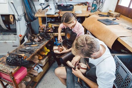 Woman and man shoemaker working together in the workshopの写真素材