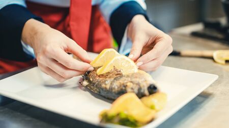 Head chef in restaurant putting food on a dish soon to be served finishing it