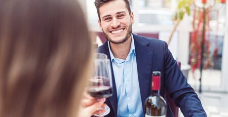 Man and woman enjoying a glass of red wine with their meal having a great timeの写真素材