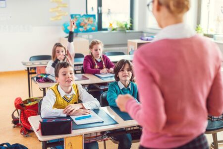 Teacher with her students in class at elementary school giving them an educationの写真素材