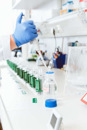 Closeup of a doctor hands using dropper to remove liquid from bottle for sampling