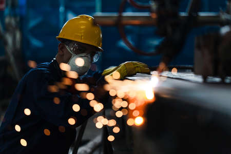 Asian worker wearing protective equipment while using CNC plasma cutterの写真素材