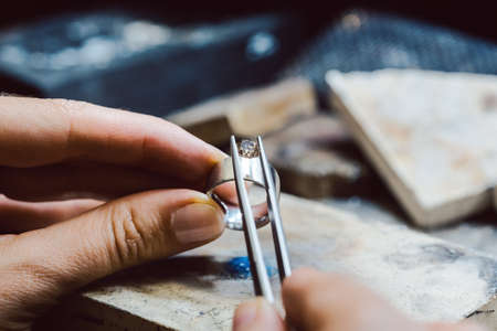 Closeup of Jeweler setting a precious stone with pincers on a ringの写真素材