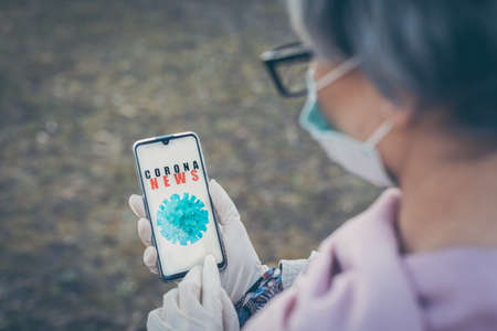 Senior woman with Covid-19 app looking at her phoneの写真素材