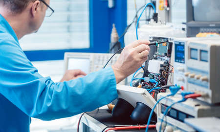 Electronics engineer man troubleshooting defects in a hardware product on his test benchの写真素材