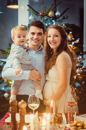 Happy family with toddler and pregnant wife celebrating Christmasの写真素材