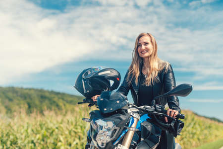Beautiful woman on a motorcycle looking at the road ahead on summer day