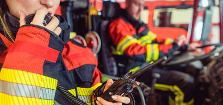 Fire fighter woman on duty using the radio in the fire truckの写真素材