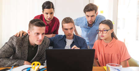 Front view of office team working on laptop in officeの写真素材