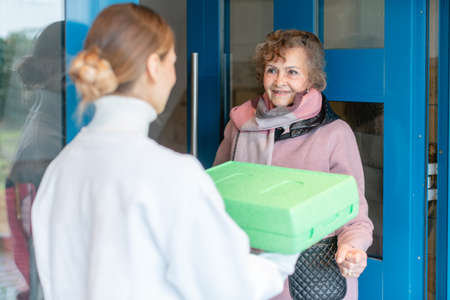 Volunteer delivering a hot meal to door of senior citizenの写真素材