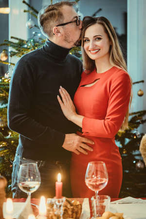 Middle aged couple in romantic pose in front of Christmas tree in seasonal spiritの写真素材