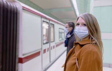 People in public transport wearing covid-19 face mask while train arrivesの写真素材