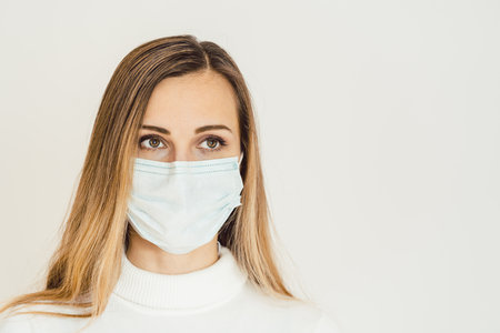 Anxious woman with face mask worried about the Covid-19 outbreak staying at homeの写真素材
