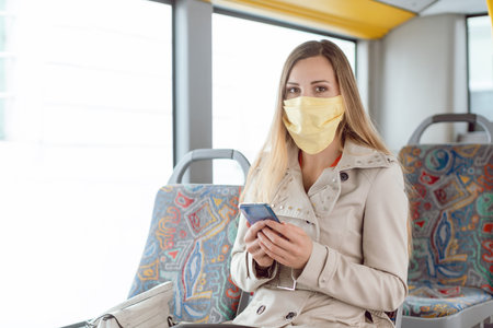 Woman using public transport during covid 19 crisis wearing face maskの写真素材