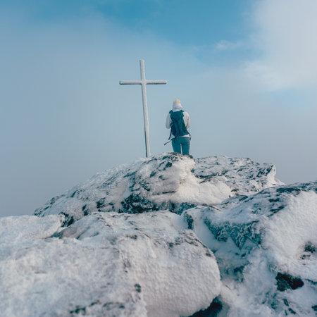 Woman standing near summit cross on a mountain summitの素材 [FY310162163931]