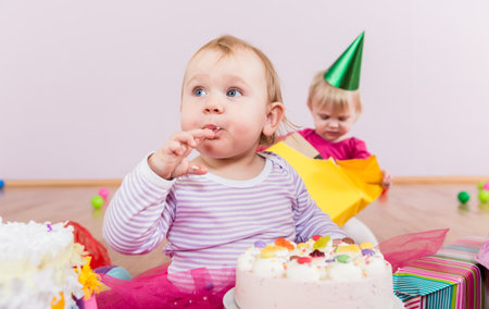 Toddler eating birthday cake in kindergartenの写真素材