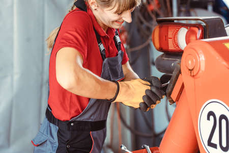 Woman machinist working with wrench of a farm machine doing some fixing or maintenanceの写真素材