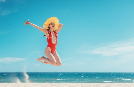 Beautiful woman enjoying her beach vacation jumping high having funの写真素材