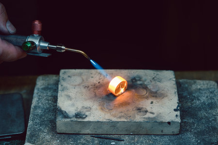 Goldsmith or jeweler heating up a ring with blue flame to work on that piece of jewelryの写真素材