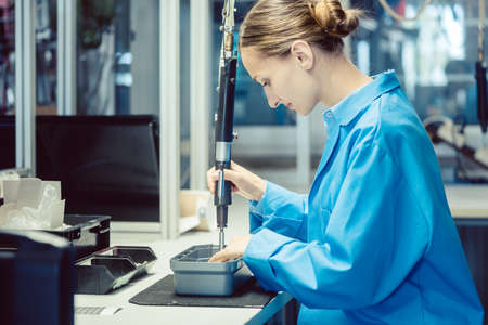 Woman in factory assembling a product using toolsの写真素材
