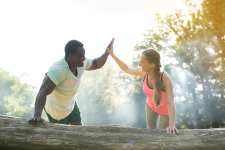 Fitness coach gives some motivation to woman doing push-ups with handshakeの写真素材