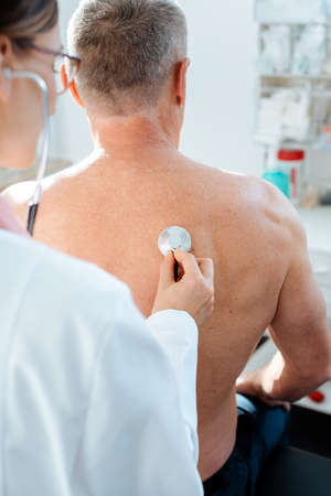 Doctor using stethoscope to check lung function on back of manの写真素材