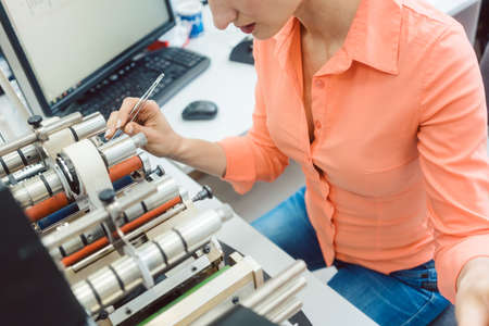Labels to be printed on being inserted into printing machine by womanの写真素材