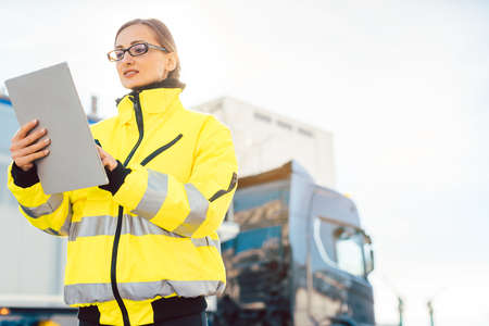 Manager checking in contents of delivery into the ERP system standing in front of delivery truckの写真素材