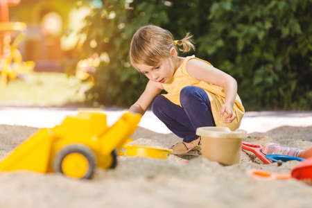 Little girl having lots of fun with her toys playing in the sandbox outdoorsの写真素材